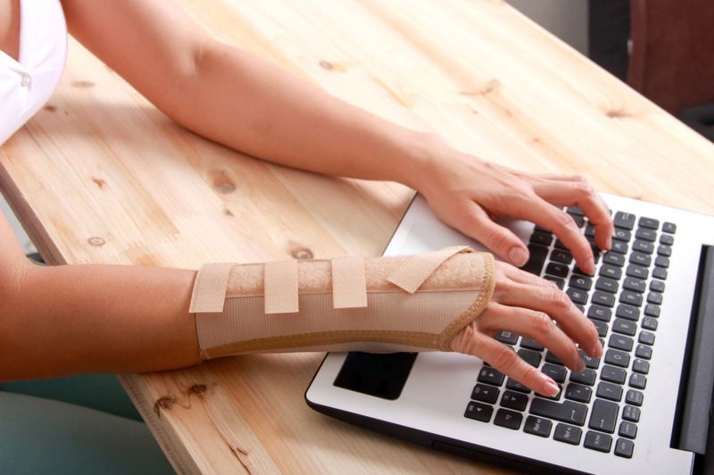 Woman With Carpal Tunnel Typing On Laptop