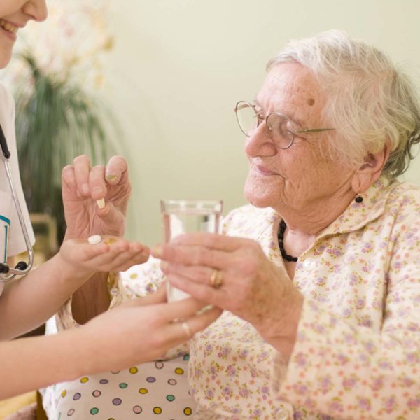 Nurse Giving Medication To Elderly Patient