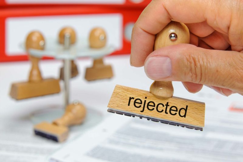 Man Holding Stamp That Says "Rejected"