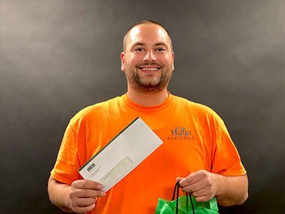 Man In Orange Shirt Holding A Check